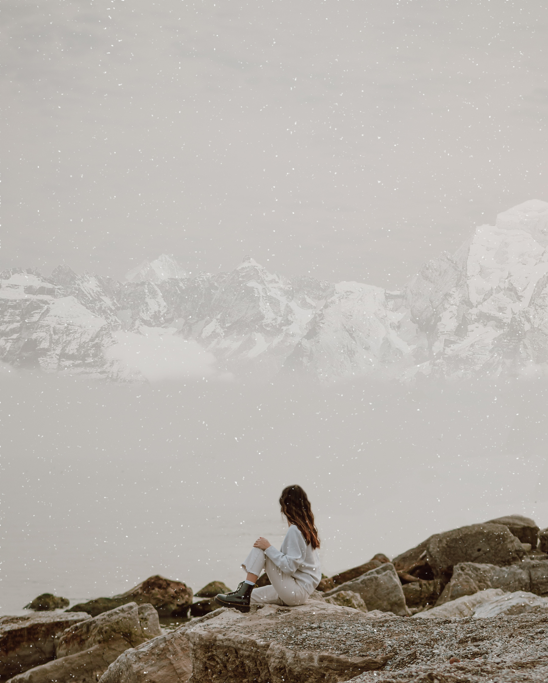 Faceless traveler contemplating sea and snowy mountains in winter